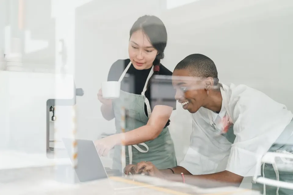 Two young baristas working together behind a café counter